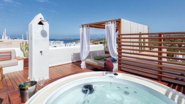 A rooftop terrace with a hot tub, wooden pergola, and a view of the sea.