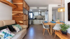 A modern kitchen with white cabinets, a wooden dining table, and a built-in oven.