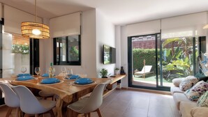 A modern dining area with a wooden table set for four, white chairs, and a hanging light fixture.
