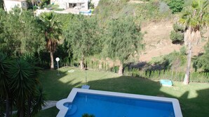 Ein Swimmingpool, umgeben von üppiger Vegetation und einer hügeligen Landschaft.