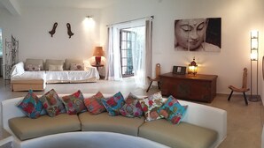 A living room with a sofa, a bed, a wooden cabinet, and a Buddha painting. - Beautiful Villa in front of the sea. House in first line of sea. (Santa Eulària des Riu)