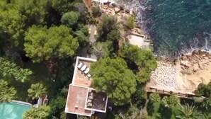 An aerial view of a coastal property with a swimming pool, a patio area, and a beach. - Beautiful Villa in front of the sea. House in first line of sea. (Santa Eulària des Riu)