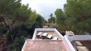 A rooftop terrace with a view of the sea, surrounded by trees. - Beautiful Villa in front of the sea. House in first line of sea. (Santa Eulària des Riu)