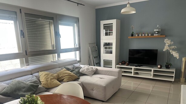 Ett modernt vardagsrum med en soffa, en tv och en matplats med ett bord och stolar.
