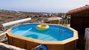 An outdoor swimming pool with a wooden deck, a hose, and a green inflatable ring.