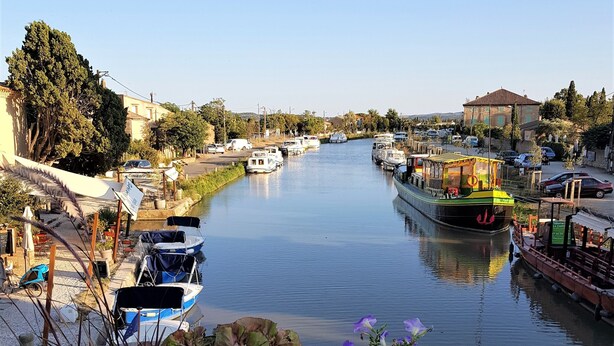 A canal with boats, a bridge, and buildings along the water. - Villagehouse, AC, pool, unoverlooked patio, stores restaurants walking distance (Saint-Nazaire-D'aude)