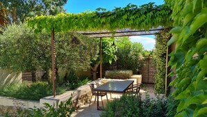 A garden patio with a pergola, seating area, and lush greenery. - Villagehouse, AC, pool, unoverlooked patio, stores restaurants walking distance (Saint-Nazaire-D'aude)