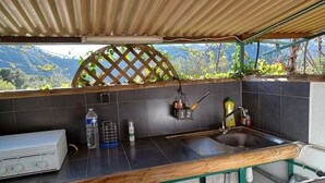 A kitchen with a gas stove, a sink, and a view of mountains.
