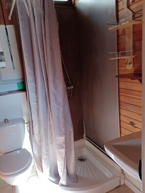 Ein kleines Badezimmer mit Dusche, Toilette und Waschbecken.