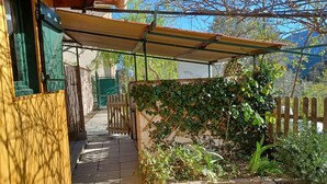 A covered outdoor area with a wooden fence, a pathway, and greenery.