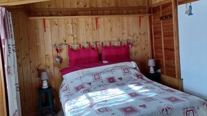 A wooden-paneled room with a bed, pillows, and a nightstand.