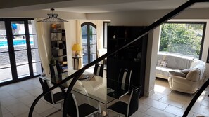 Een moderne woonkamer met een glazen trap, een bank en een boekenkast.