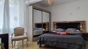 A bedroom with a bed, a chair, a wardrobe, and a TV.