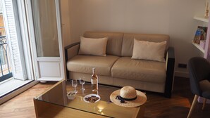 A modern living room with a glass coffee table, a beige sofa, and a wicker hat. - Appart Aix Mazarin 3 stars-T2 with air conditioning in the historic city centre (Aix-en-Provence)