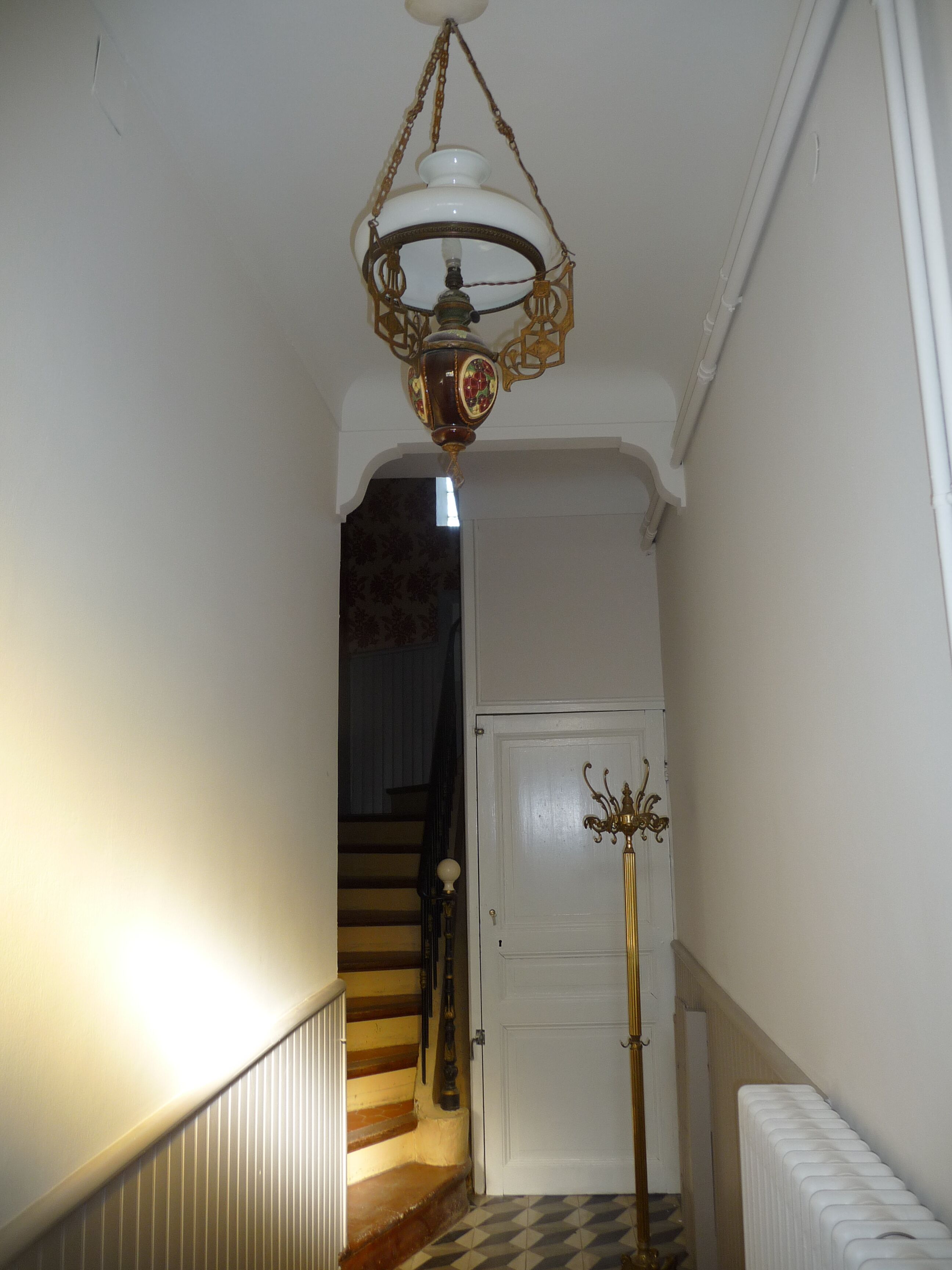 Un pasillo con una escalera, un radiador y una puerta.