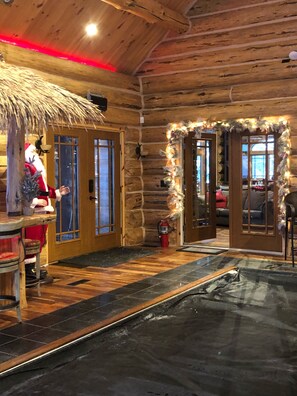 A log cabin interior with a wooden ceiling, stone walls, a thatched roof decoration, and a Christmas display. - Luxury Custom Built Log Cabin with indoor pool and spa on Lake Michigamme (Champion)