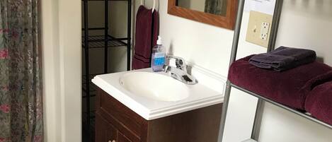 A bathroom with a white sink, dark wooden cabinet, white toilet, and a metal towel rack.