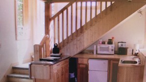 Une pièce avec un escalier, un bureau et une chaise.