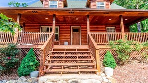 A two-story log cabin with a front porch, stone steps, and a wooden fence. - Sleeps 12, Pool, Marina, Quiet Side of Table Rock (Cassville)