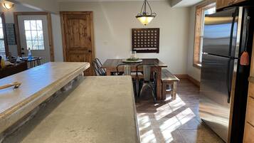 Una cocina con una isla grande, armarios de madera, un refrigerador de acero inoxidable y una lámpara colgante.