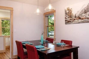 A dining area with a wooden table, red chairs, and a painting of a forest scene. - Clean, Private, Historic, Downtown Bozeman Home (Bozeman)