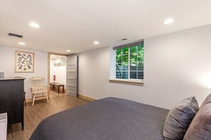 A bedroom with a bed, a chair, a desk, a window, and a door. - Clean, Private, Historic, Downtown Bozeman Home (Bozeman)