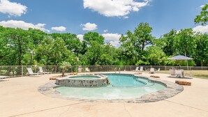 Una piscina con hidromasaje, rodeada de sillones de descanso y un borde de piedra.
