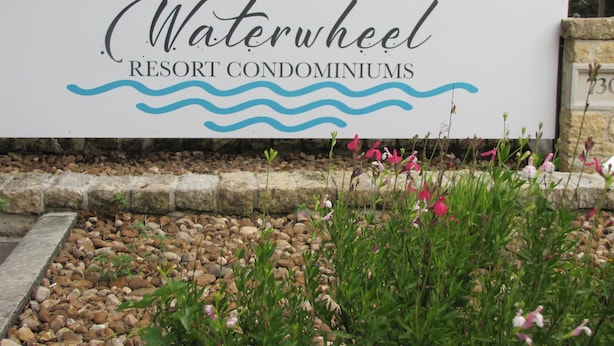 Señal para Waterwheel Resort Condominiums, con un logotipo que presenta un sol y olas.