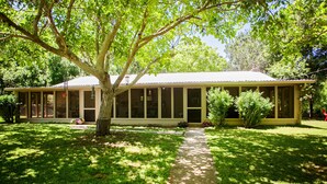 A single-story building with a covered porch, surrounded by well-maintained grass and trees.