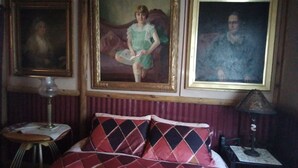 Une pièce comprenant un lit, une table et deux tableaux accrochés au mur.