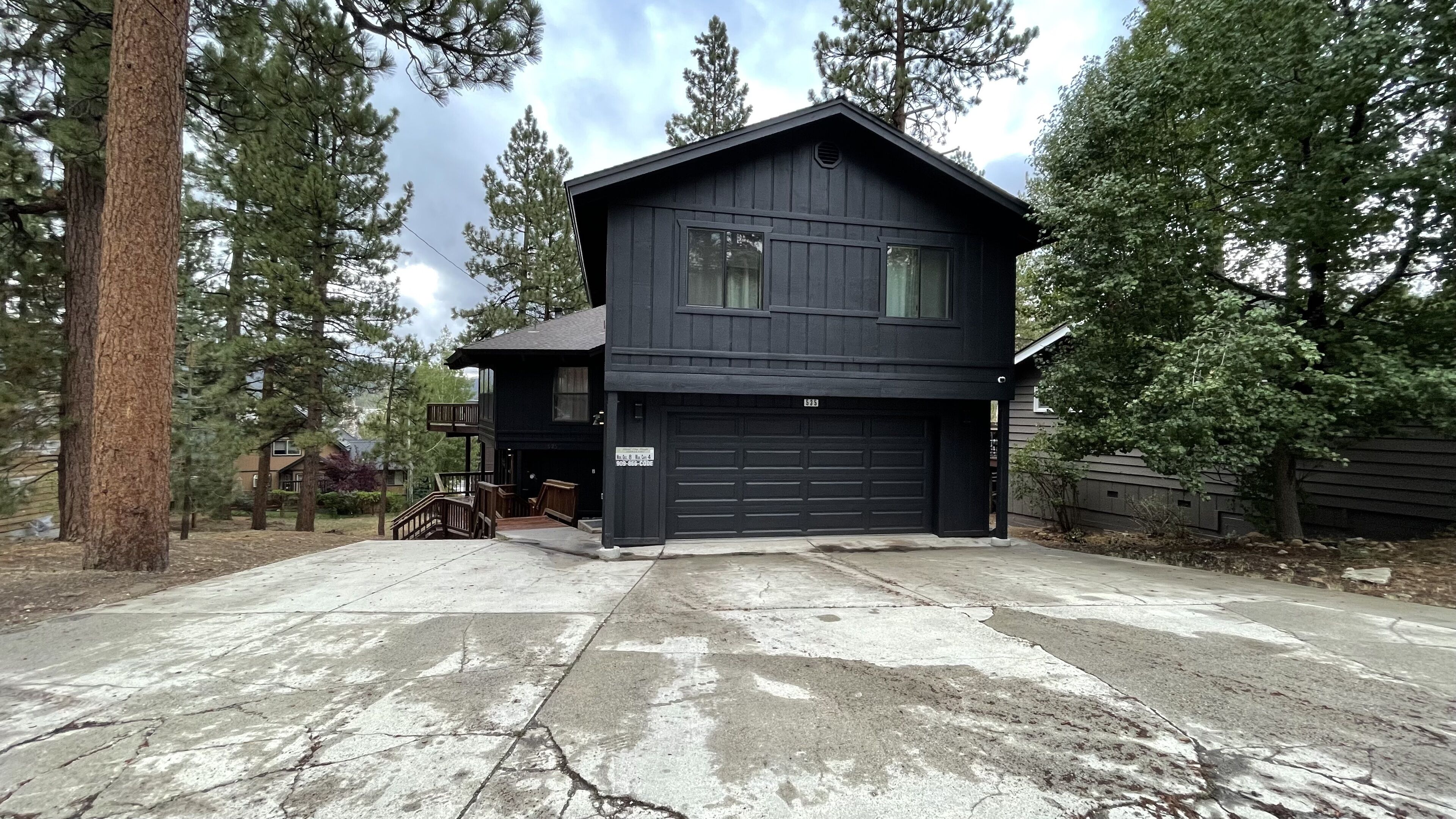 A two-story house with a garage, surrounded by trees.