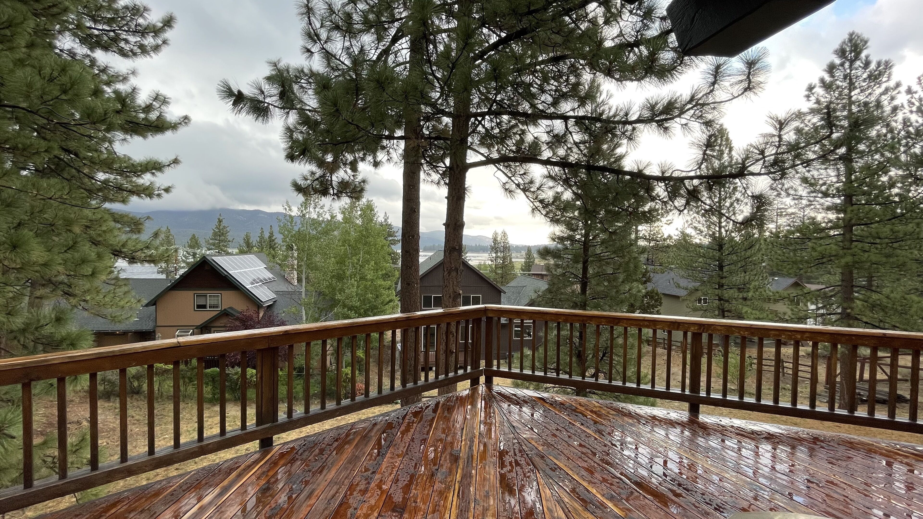 Una terraza de madera con vista a casas y árboles.