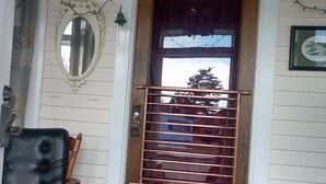 A wooden door with a metal gate, a black leather chair, a brown leather bench, a mirror, and a doormat.