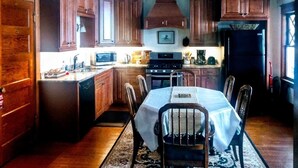 A kitchen with wooden cabinets, a dining table with chairs, a microwave, stove, and a refrigerator.