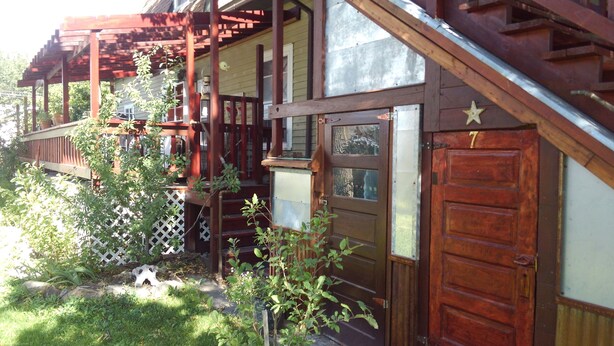 A wooden house with a porch, a door with a star-shaped decoration, and a small garden area.