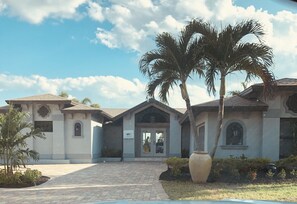 A building with a tiled entrance, palm trees, and a large vase. - Breathtaking Views! Dock is in! (Cape Coral)