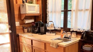 A wooden kitchen with a built-in microwave, coffee maker, and sink.