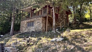 A stone building with a wooden balcony, surrounded by trees.