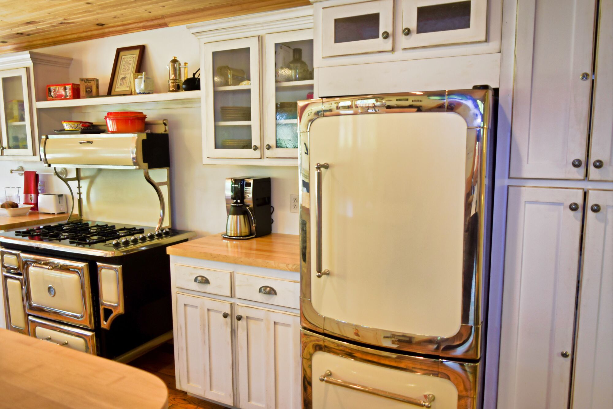 A kitchen with a stove, coffee maker, and a refrigerator.
