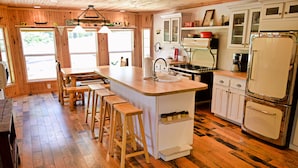 A kitchen with wooden floors, a central island with stools, white cabinets, and a vintage refrigerator. - Beautiful Mountain Top Private Log Cabin Lake And Mountain Views  Pet Friendly (Butler)