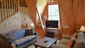 A cozy cabin interior with a wooden interior, a sofa, a coffee table, and a television. - Beautiful Mountain Top Private Log Cabin Lake And Mountain Views  Pet Friendly (Butler)