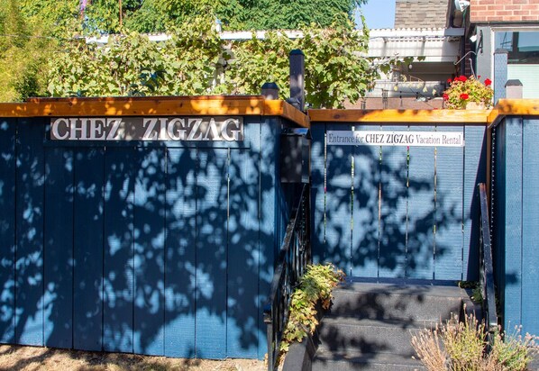 A blue gate with 'CHEZ ZIGZAG' and 'Entrance for CHEZ ZIGZAG Vacation Rental' signs.