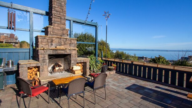 Eine Außenpatio mit Kamin aus Stein, Sitzgelegenheiten und Meerblick.