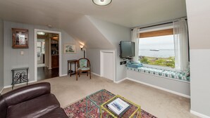 A living room with a view of the water, a television, and a cozy seating area.