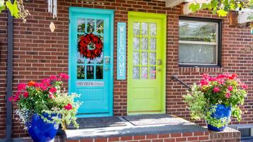 A brick building with a turquoise and lime green door, a 'WELCOME' sign, and a 'Chez ZIGZAG Entrance' sign.