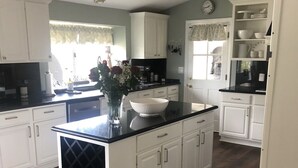 Una cocina con armarios blancos, encimera negra y suelo de madera.