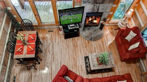 A cozy living room with a fireplace, a television, and red sofas. - MOUNTAIN HIDEAWAY - AUTHENTIC LOG CABIN MINUTES TO PARKWAY AND ATTRACTIONS!!! (Pigeon Forge)