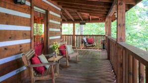 A wooden porch with a bench and a chair, a hanging lantern, and a sign that says "BEWARE OF THE BEAR". - MOUNTAIN HIDEAWAY - AUTHENTIC LOG CABIN MINUTES TO PARKWAY AND ATTRACTIONS!!! (Pigeon Forge)