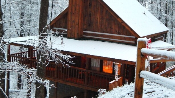 A wooden cabin with a steep roof, surrounded by a snowy forest. - MOUNTAIN HIDEAWAY - AUTHENTIC LOG CABIN MINUTES TO PARKWAY AND ATTRACTIONS!!! (Pigeon Forge)