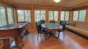 A wooden-floored room with a foosball table, a green felt poker table, and a sofa with a patterned pillow. - White Water River Cabin near Helen, GA-Kayak, tube, fish, hike, in wine country (Cleveland)